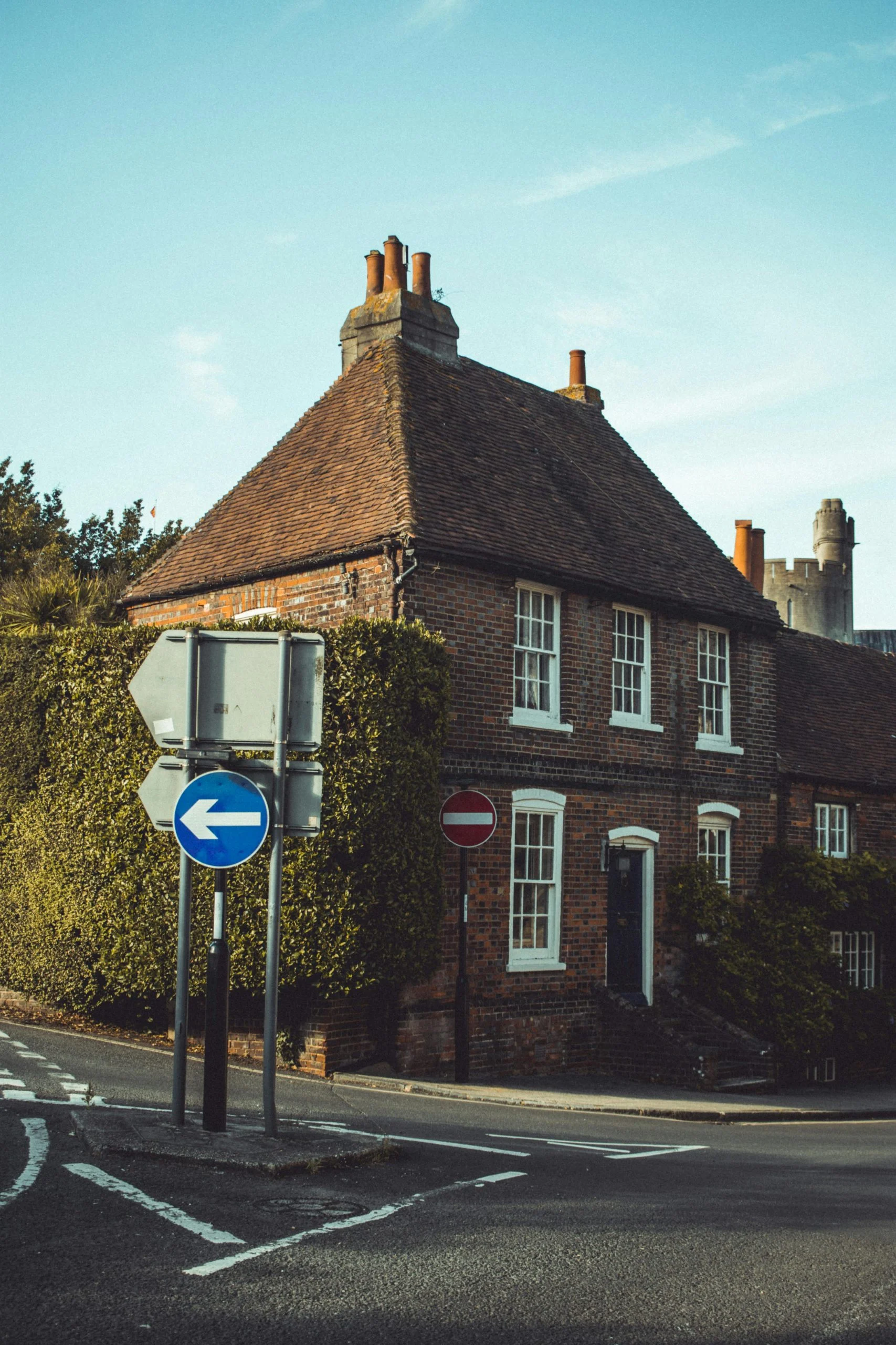 British house with ivy on it on the corner of a road