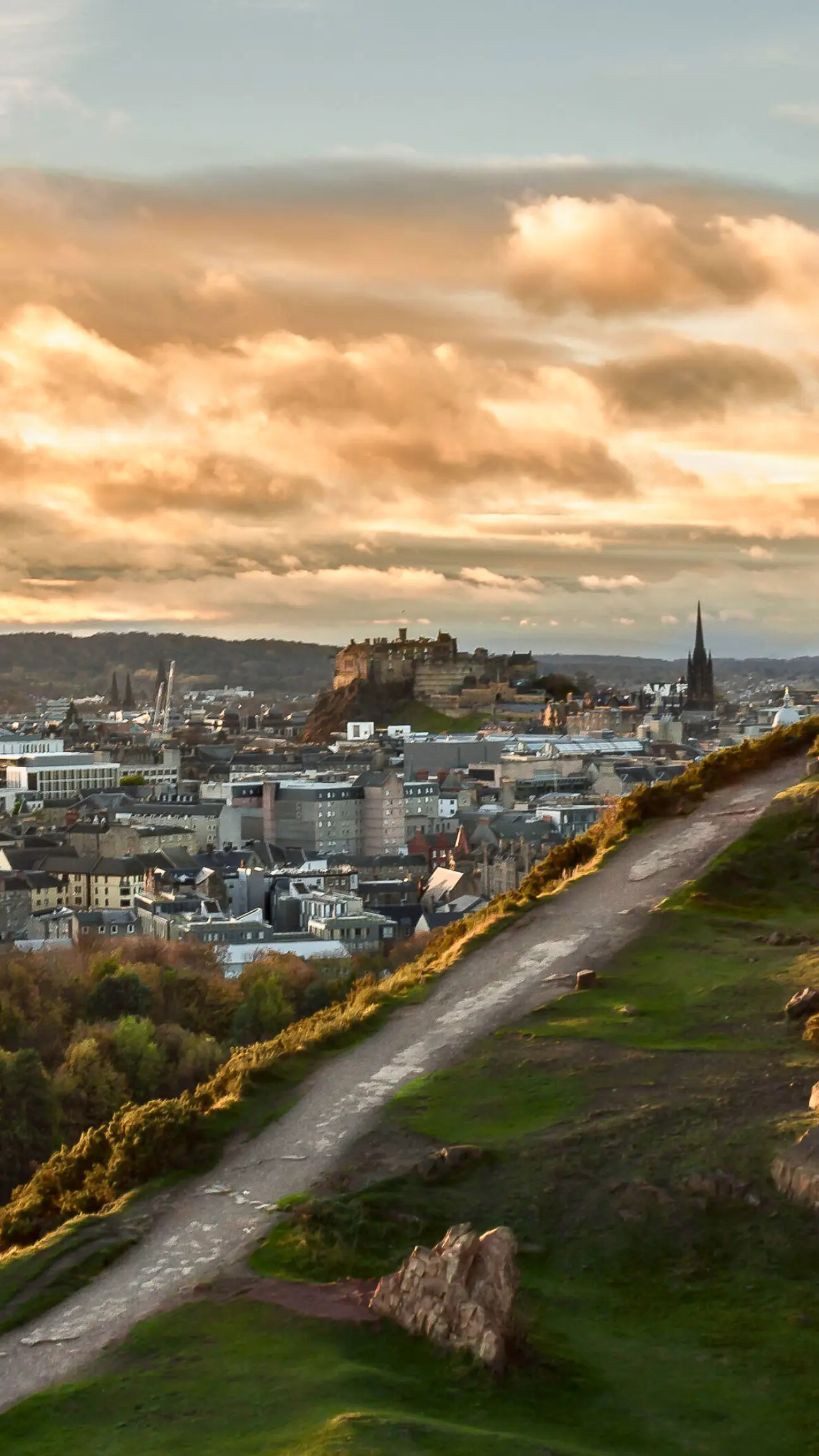A scenic view of Edinburgh at sunset with Edinburgh Castle overlooking the city, used to highlight the importance of protecting local homes with professional gutter cleaning.