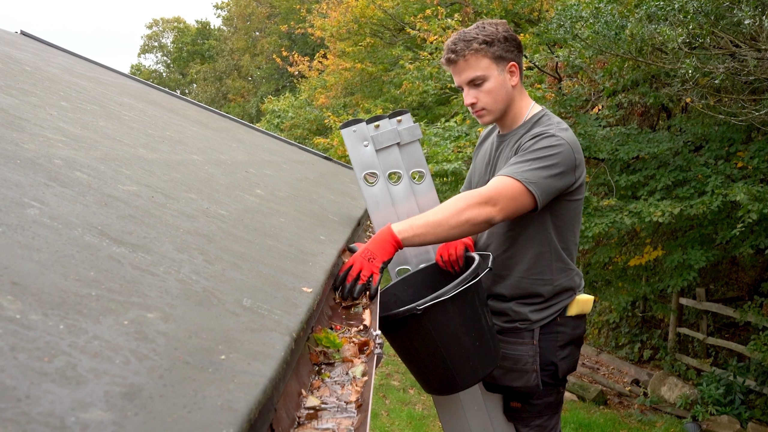 a cleaner cleaner gutters on a ladder by hand